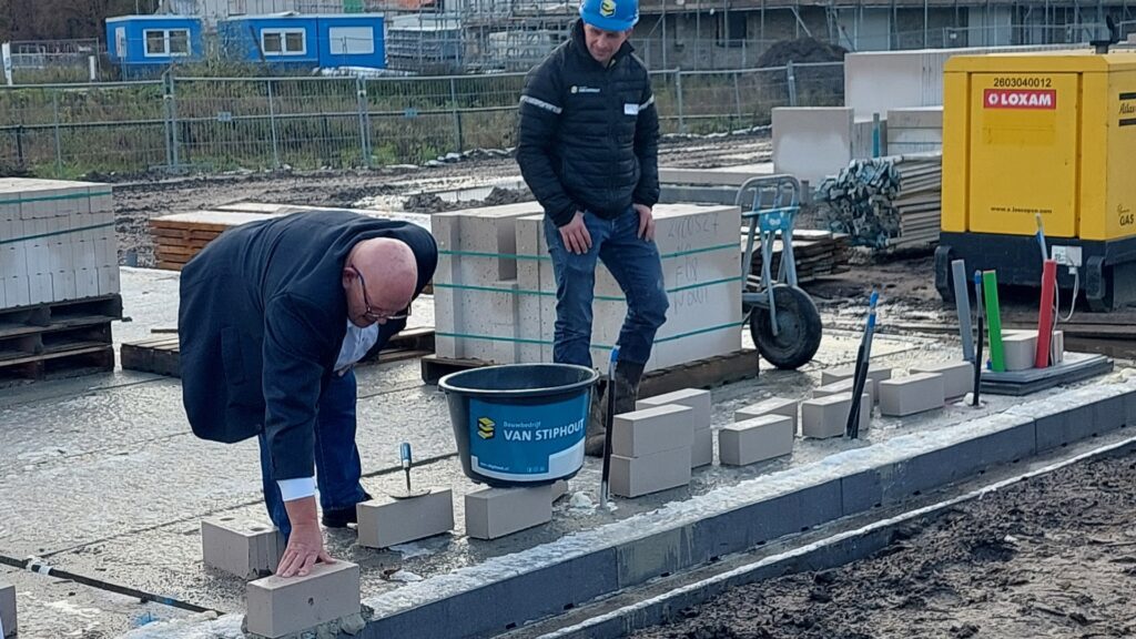 Onder toeziend oog van de uitvoerder legt wethouder Ben Brands een symbolische eerste steen